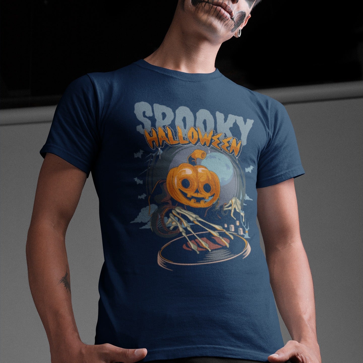 A black background features the distressed light blue text "SPOOKY" and distressed orange text "HALLOWEEN" with a white outline at the top. Below, a large, smiling jack-o'-lantern (pumpkin head) wearing a dark cloak is shown operating a DJ turntable. Skeletal hands with long fingers extend from the cloak over the turntable, manipulating it. In the background, there's a large, pale full moon, silhouetted bats flying, and cloud-like mist. The design represents a Halloween-themed DJ ready for a spooky music pa