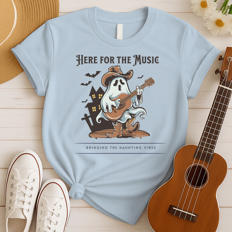 A light grey background features a stylized illustration of a white ghost wearing a brown cowboy hat and cowboy boots. The ghost is playing a brown acoustic guitar. Behind the figure, dark silhouettes of a haunted house and several bats are visible. At the top, the text reads "HERE FOR THE MUSIC" and at the bottom, "BRINGING THE HAUNTING VIBES". The design blends Halloween, music, and western themes.