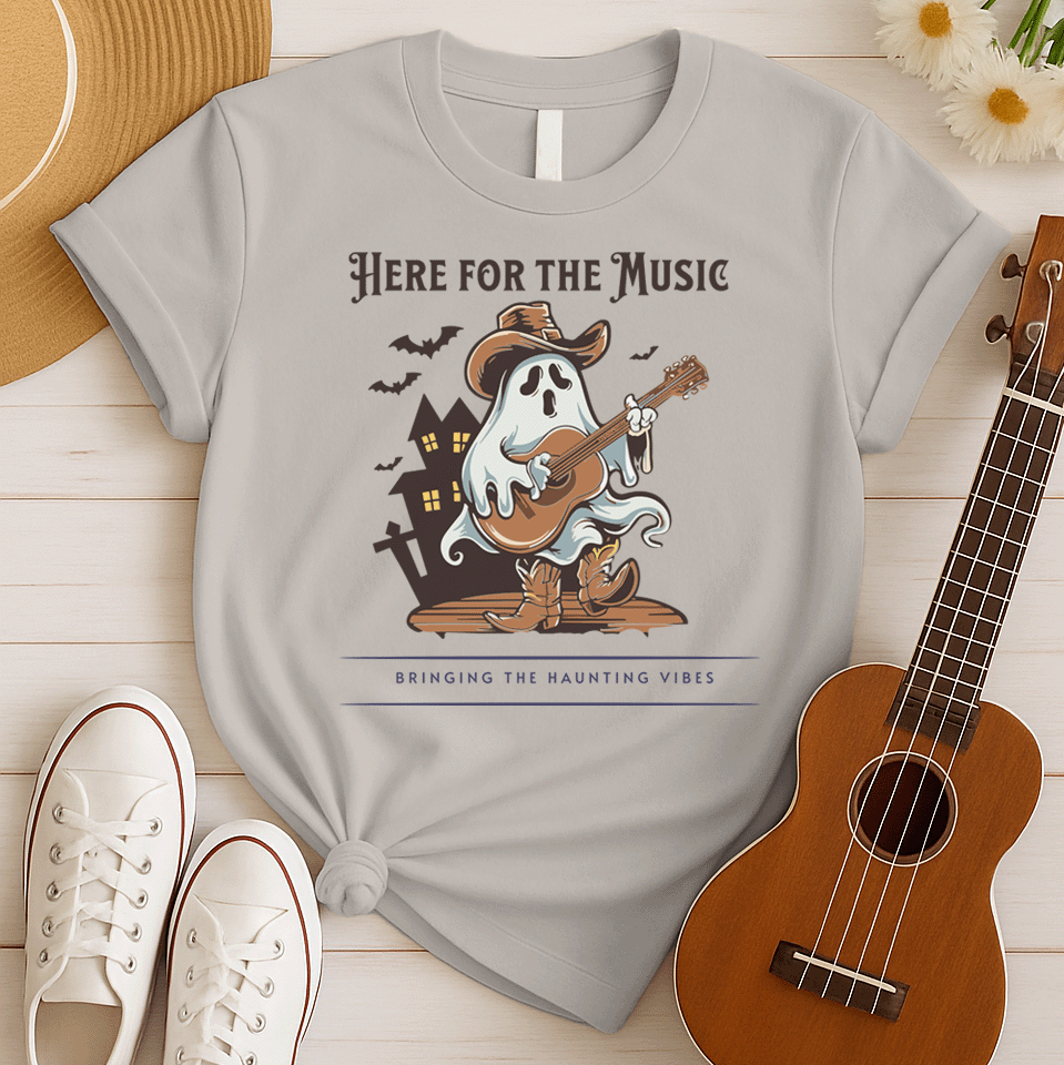 A light grey background features a stylized illustration of a white ghost wearing a brown cowboy hat and cowboy boots. The ghost is playing a brown acoustic guitar. Behind the figure, dark silhouettes of a haunted house and several bats are visible. At the top, the text reads "HERE FOR THE MUSIC" and at the bottom, "BRINGING THE HAUNTING VIBES". The design blends Halloween, music, and western themes.