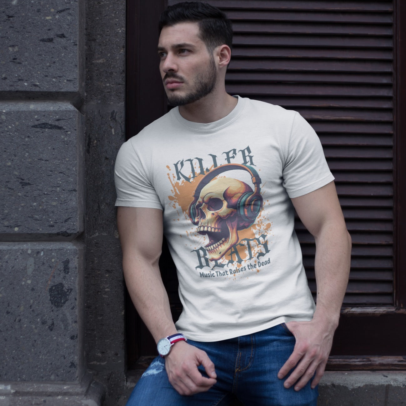 A light grey background with orange paint splatters features a stylized, detailed, orange and yellow human skull wearing large, teal and blue headphones. Distressed grey text above reads "KILLER" and below, "BEATS". Below that, smaller dark grey text says "Music That Raises the Dead". The design is a bold representation of music power and skull art.