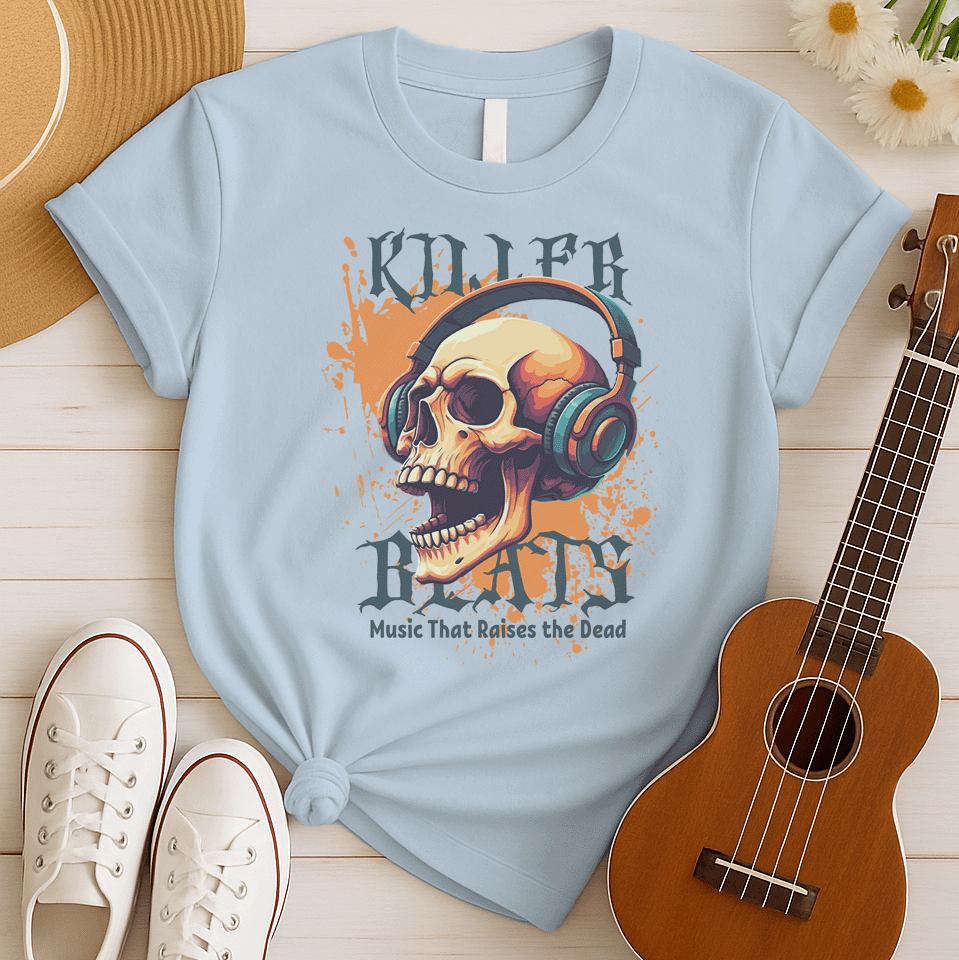 A light grey background with orange paint splatters features a stylized, detailed, orange and yellow human skull wearing large, teal and blue headphones. Distressed grey text above reads "KILLER" and below, "BEATS". Below that, smaller dark grey text says "Music That Raises the Dead". The design is a bold representation of music power and skull art.