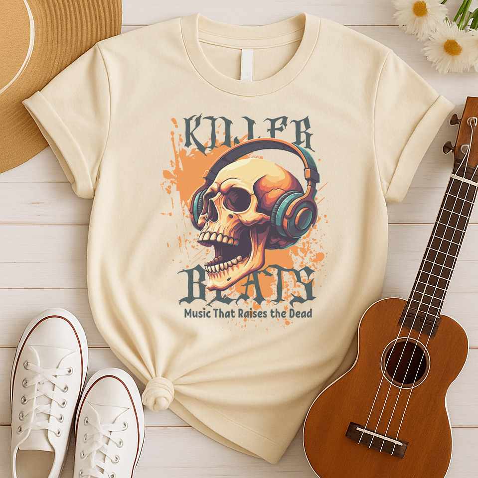 A light grey background with orange paint splatters features a stylized, detailed, orange and yellow human skull wearing large, teal and blue headphones. Distressed grey text above reads "KILLER" and below, "BEATS". Below that, smaller dark grey text says "Music That Raises the Dead". The design is a bold representation of music power and skull art.