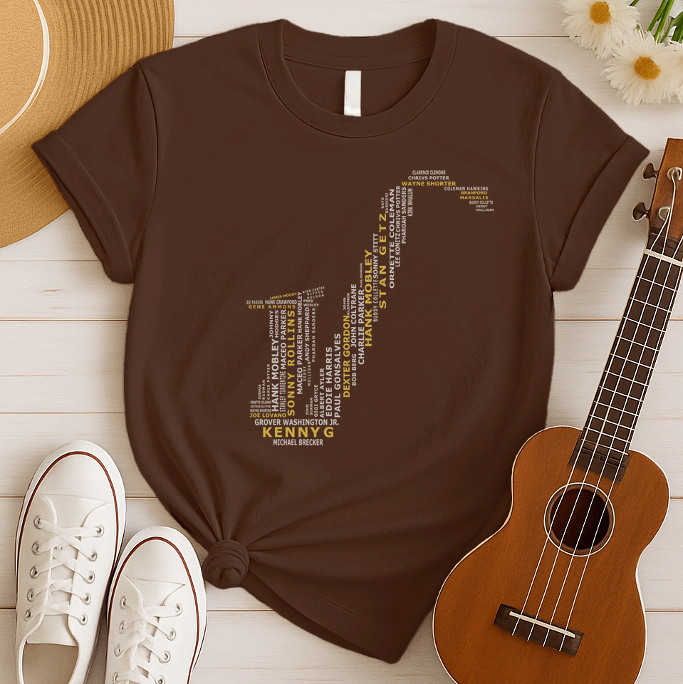 A creative typographic design forms the silhouette of a saxophone using the names of various famous jazz musicians and saxophonists. The names, in white text of varying sizes and fonts, fill the entire shape of the instrument. Prominently featured in larger, bold yellow text at the bottom is "KENNY G", with "MICHAEL BRECKER" directly below it in white, creating a visual tribute to jazz legends.