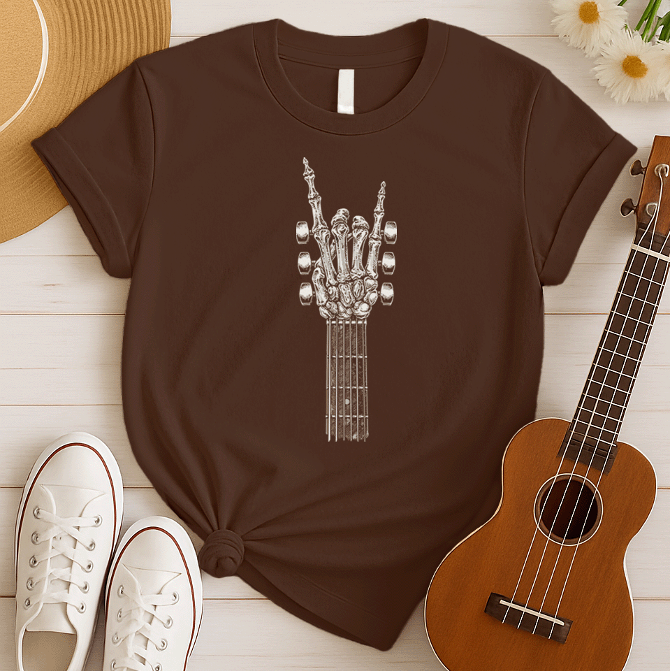 A bold graphic design depicts a skeletal hand forming the classic "rock and roll" sign, with the index and pinky fingers extended upwards, and the thumb holding down the middle two fingers. The hand, rendered in a detailed bone-like texture with shades of white and gray, is positioned at the top of a guitar fretboard, which features brown and white frets and tuning pegs on either side. This powerful image symbolizes the enduring spirit of rock music and its connection to the eternal nature of this genre.