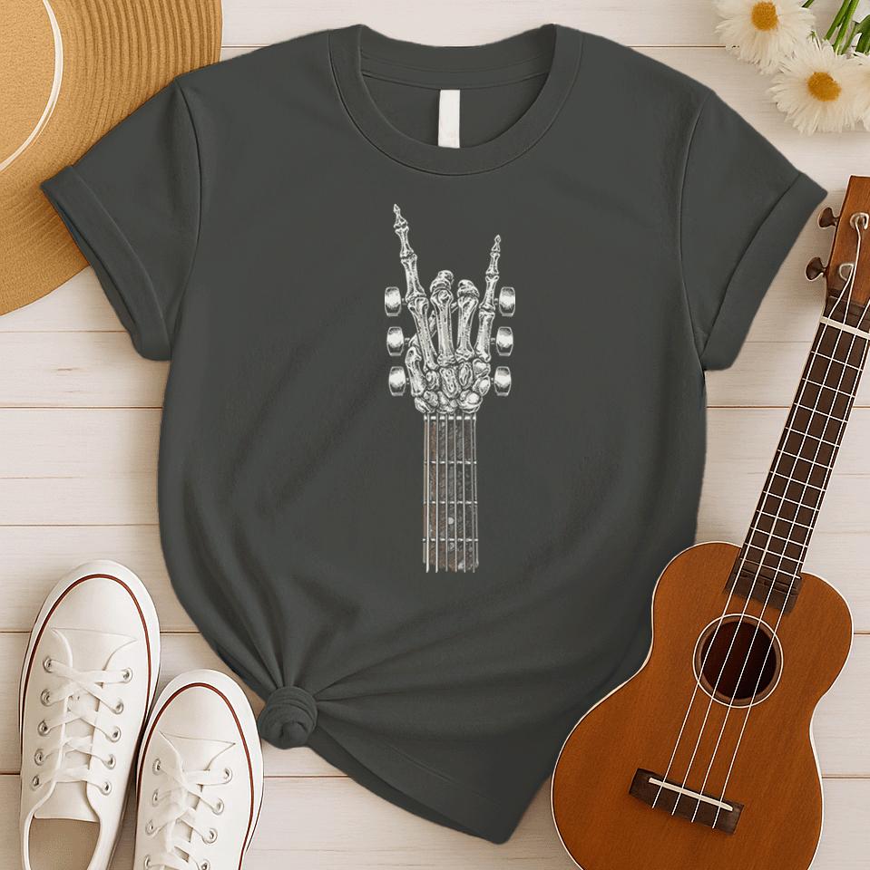 A bold graphic design depicts a skeletal hand forming the classic "rock and roll" sign, with the index and pinky fingers extended upwards, and the thumb holding down the middle two fingers. The hand, rendered in a detailed bone-like texture with shades of white and gray, is positioned at the top of a guitar fretboard, which features brown and white frets and tuning pegs on either side. This powerful image symbolizes the enduring spirit of rock music and its connection to the eternal nature of this genre.