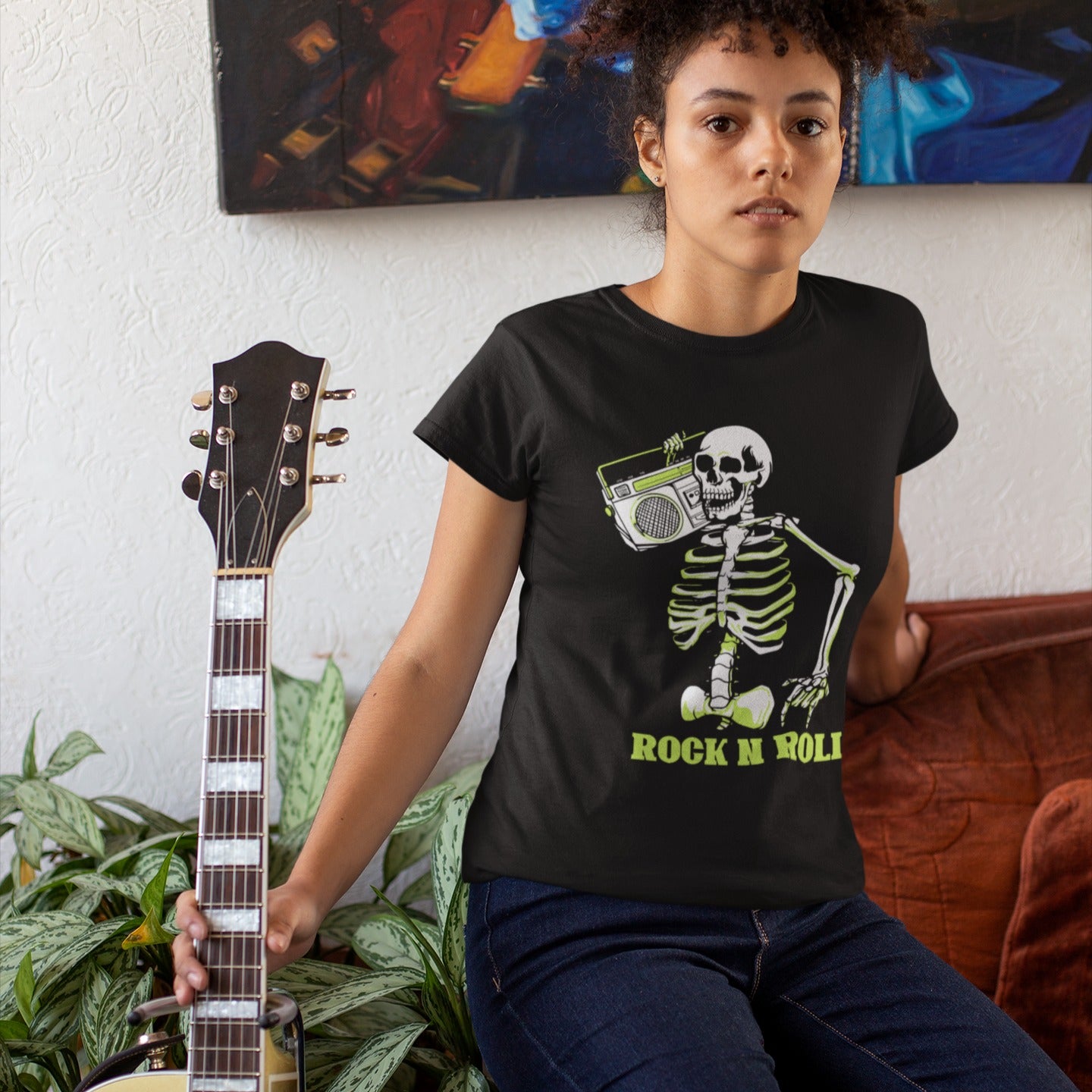 A striking graphic design features a full skeleton, rendered in white with a vibrant lime green glow on its bones, posed in a dynamic, walking stance. The skeleton holds a detailed, white outline of a retro boombox over its right shoulder. Below the skeleton, the bold, lime green text "ROCK N ROLL" is prominently displayed, creating a cool, energetic, and slightly spooky tribute to classic music.