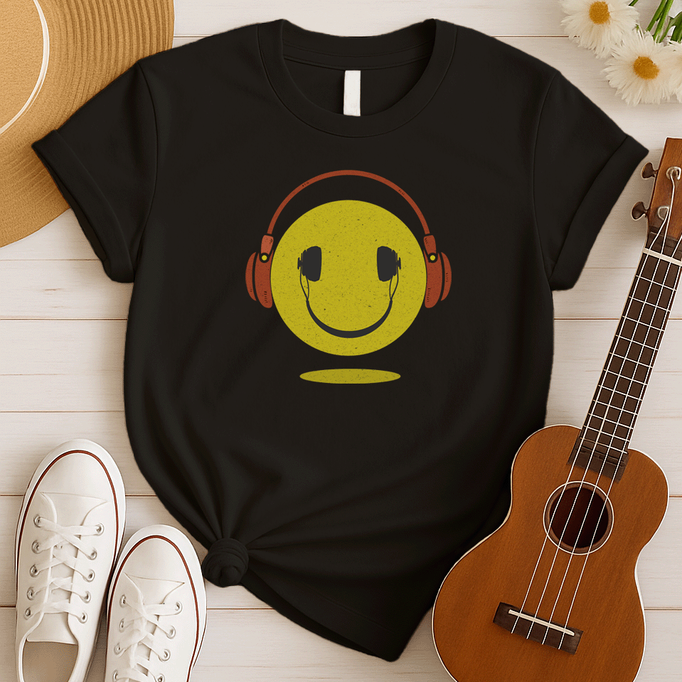 A bold and expressive graphic features a textured, distressed yellow smiley face with a prominent black smile and eyes. Large, rustic orange over-ear headphones, also with a distressed texture, are worn on top of the smiley face. The entire design creates a lively and vintage-inspired image that conveys happiness and a love for music.