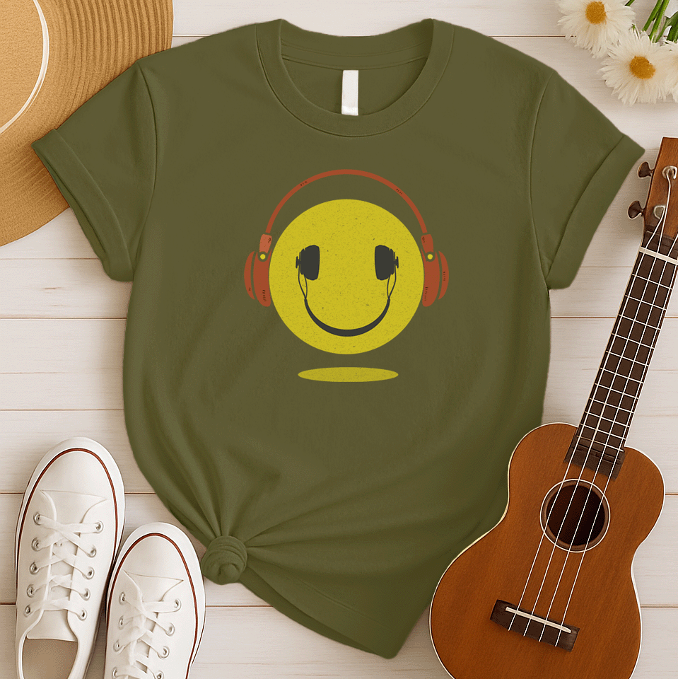 A bold and expressive graphic features a textured, distressed yellow smiley face with a prominent black smile and eyes. Large, rustic orange over-ear headphones, also with a distressed texture, are worn on top of the smiley face. The entire design creates a lively and vintage-inspired image that conveys happiness and a love for music.