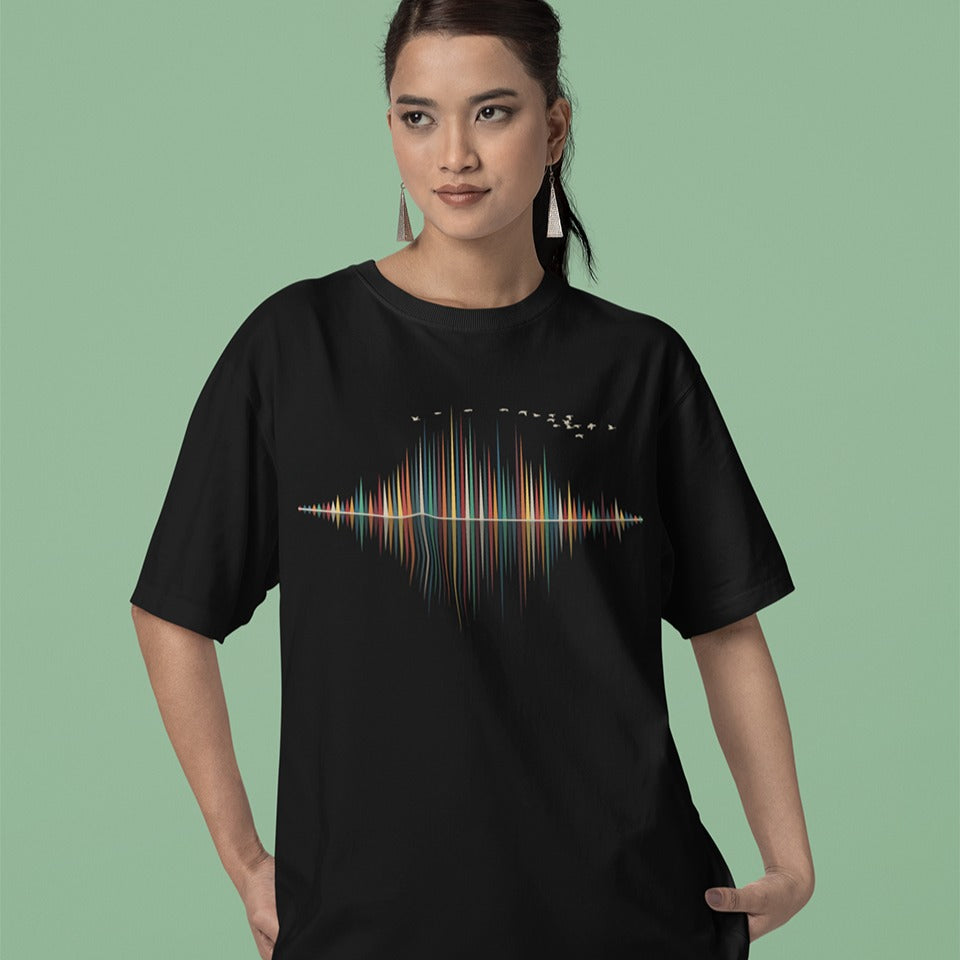 A dynamic graphic design showcases a colorful sound equalizer or sound wave, with vertical bars of varying heights in shades of red, orange, green, blue, and yellow. The bars appear to rise from and reflect into a central horizontal axis, creating a symmetrical visual representation of sound. A flock of small, light-colored birds flies in an arc across the top right of the design, adding a sense of movement. The entire vibrant composition symbolizes music, audio, or a vibrant auditory experience.