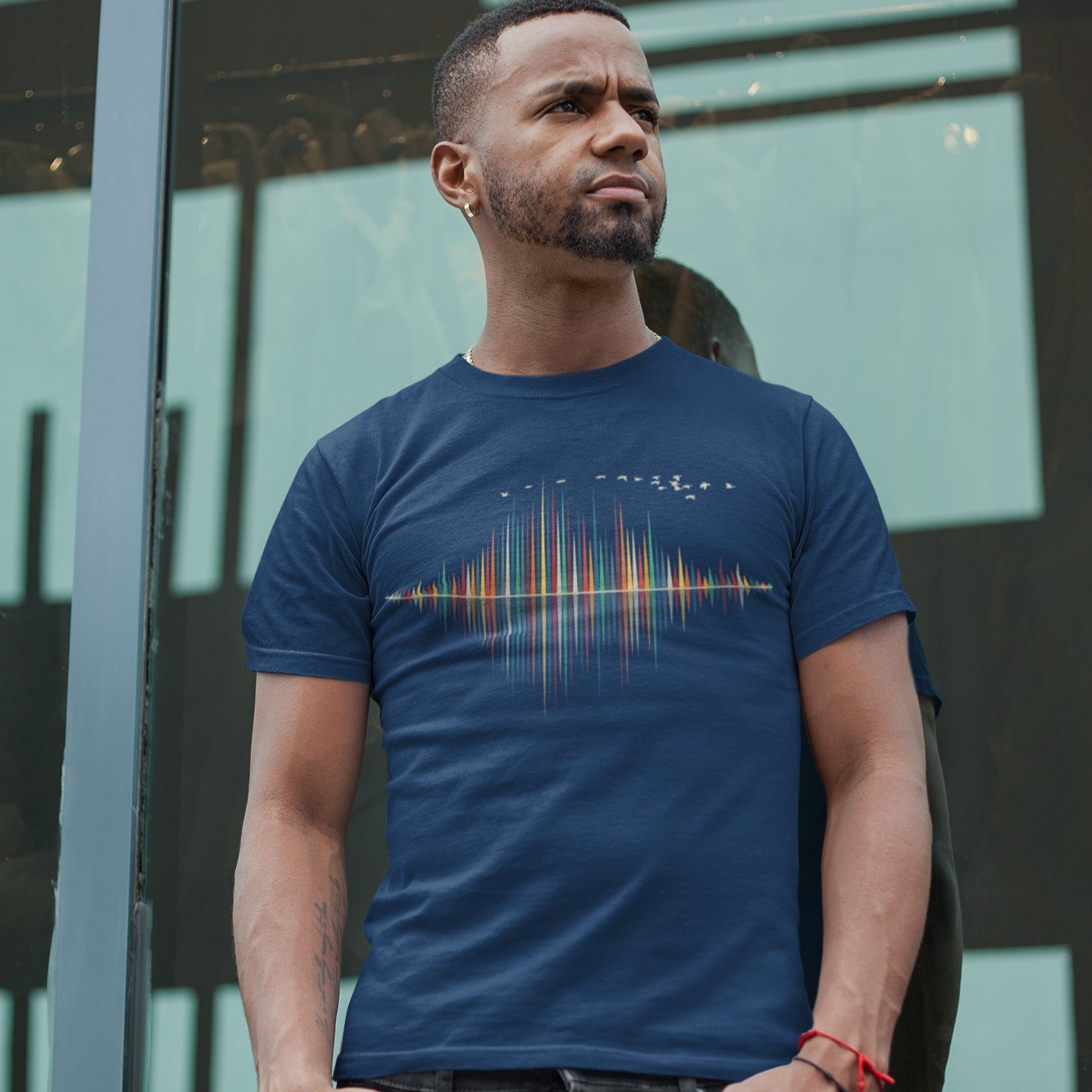 A dynamic graphic design showcases a colorful sound equalizer or sound wave, with vertical bars of varying heights in shades of red, orange, green, blue, and yellow. The bars appear to rise from and reflect into a central horizontal axis, creating a symmetrical visual representation of sound. A flock of small, light-colored birds flies in an arc across the top right of the design, adding a sense of movement. The entire vibrant composition symbolizes music, audio, or a vibrant auditory experience.