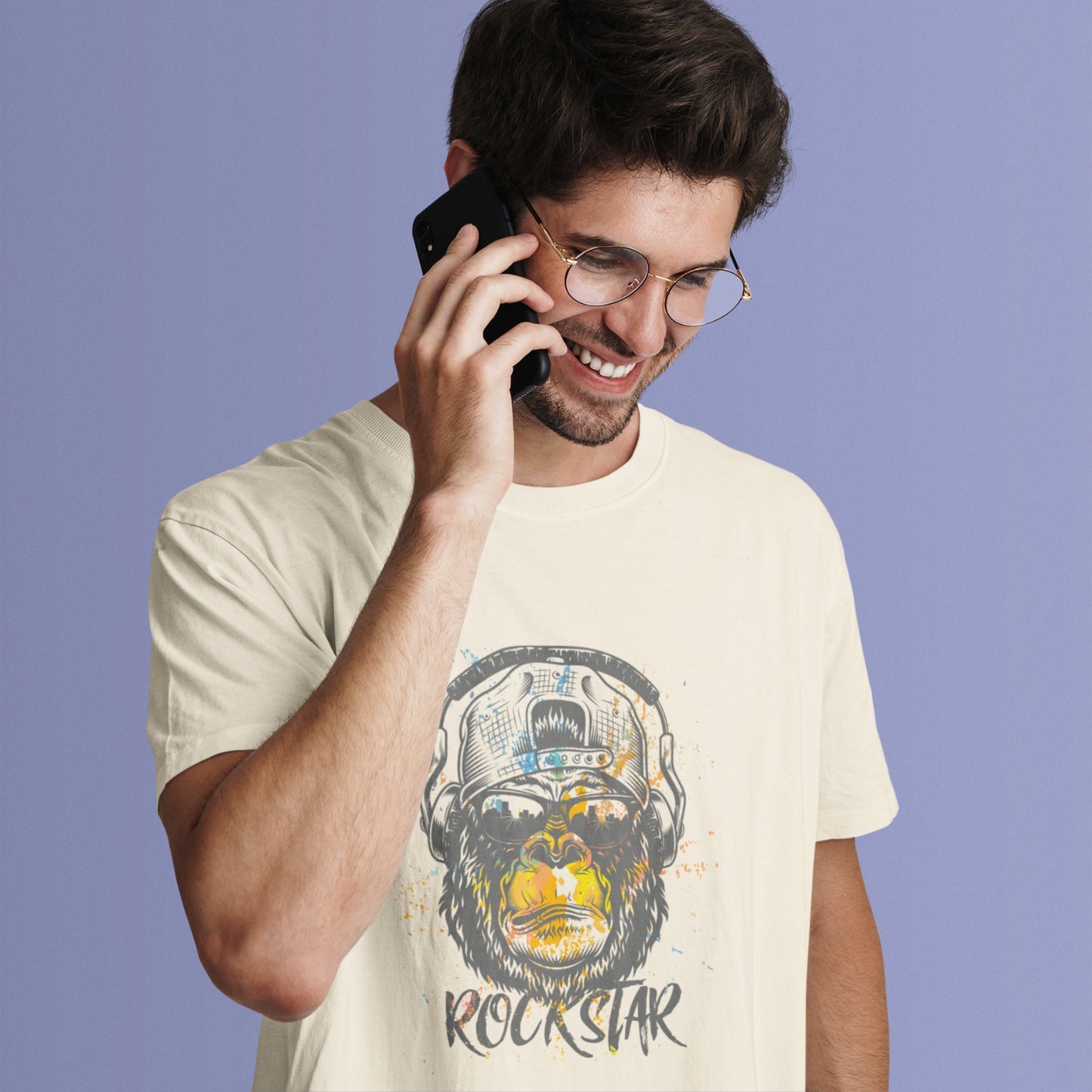 A grunge-style graphic features a detailed gorilla head wearing headphones, with the lower half of its face replaced by a textured splash of orange and yellow paint. The gorilla's fur and the headphones are rendered in shades of grey with distressed effects. Below the powerful primate, the word "ROCKSTAR" is emblazoned in a distressed white font with flecks of colorful paint matching the face. This striking design embodies raw power and musical rebellion.