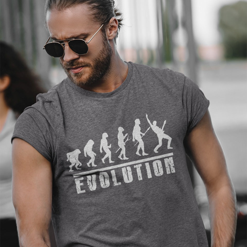 A striking graphic design illustrates the "Evolution of Man" in a sequence of white silhouettes against a black background, beginning with an ape-like figure and progressing through various stages of hominid development. The final figure in the evolutionary chain is a modern human, dynamically playing an electric guitar and raising a "rock on" hand gesture, symbolizing the evolution into a "rockstar." Below the figures, the bold, distressed white word "EVOLUTION" is prominently displayed.