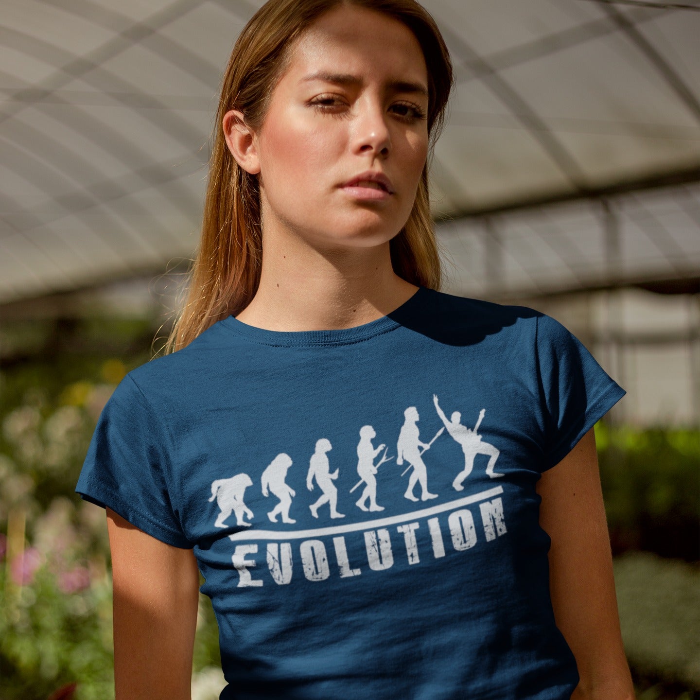 A striking graphic design illustrates the "Evolution of Man" in a sequence of white silhouettes against a black background, beginning with an ape-like figure and progressing through various stages of hominid development. The final figure in the evolutionary chain is a modern human, dynamically playing an electric guitar and raising a "rock on" hand gesture, symbolizing the evolution into a "rockstar." Below the figures, the bold, distressed white word "EVOLUTION" is prominently displayed.