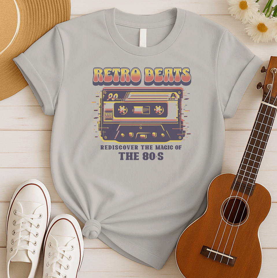 Stylized graphic of a classic audio cassette tape in red, yellow, and blue colors with a glitch effect. Large, distressed orange text above reads "RETRO BEATS". Smaller orange text below reads "REDISCOVER THE MAGIC OF THE 80S". The design evokes vintage music, 80s pop culture, and retro audio technology. Ideal for 80s enthusiasts and music lovers.