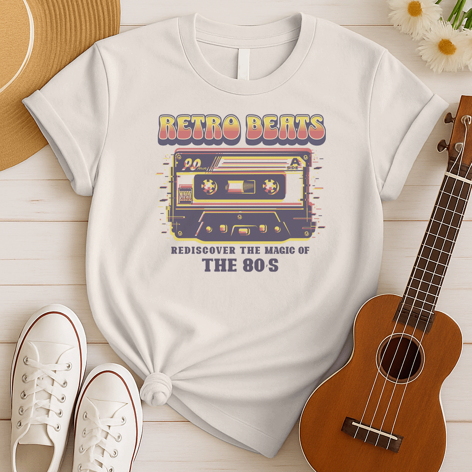 Stylized graphic of a classic audio cassette tape in red, yellow, and blue colors with a glitch effect. Large, distressed orange text above reads "RETRO BEATS". Smaller orange text below reads "REDISCOVER THE MAGIC OF THE 80S". The design evokes vintage music, 80s pop culture, and retro audio technology. Ideal for 80s enthusiasts and music lovers.