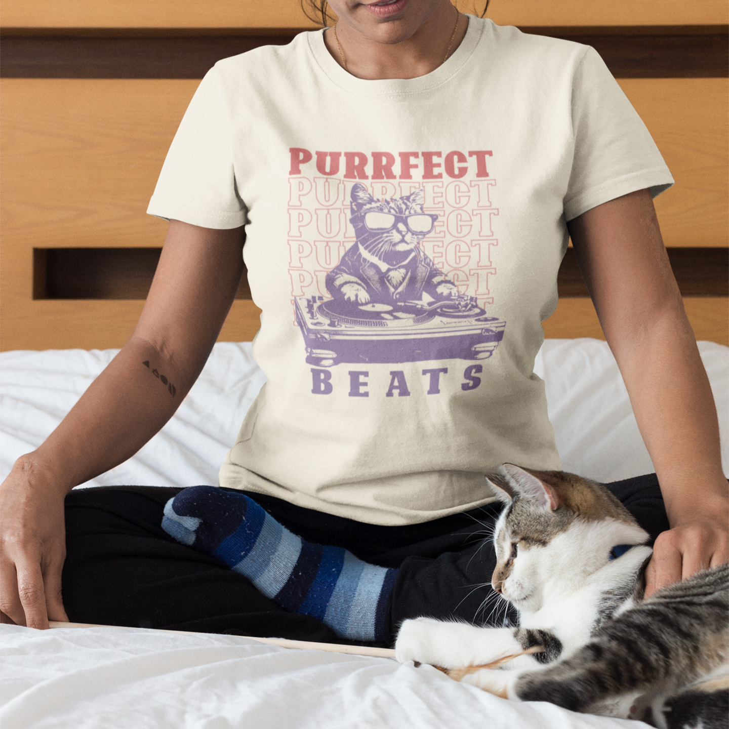 Stylized graphic of a cool purple cat wearing sunglasses and a suit jacket, confidently scratching on a large DJ turntable. Red text repeats "PURRFECT" in the background, and large purple text below reads "BEATS". The design embodies DJ culture, electronic music, and a humorous feline twist, ideal for DJs, cat lovers, and music enthusiasts.