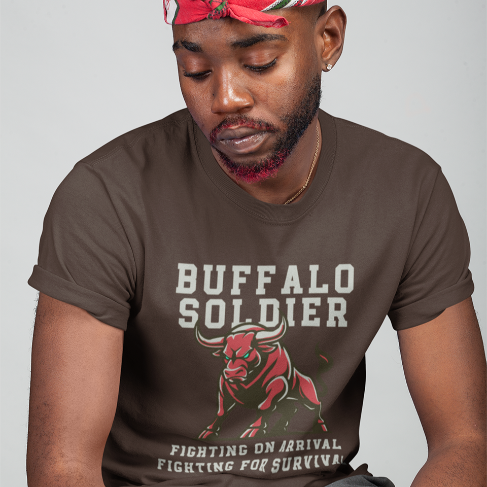 A striking graphic design features a powerfully built red bull with menacing green eyes and prominent horns, depicted in a charging or aggressive stance. The bull's body is outlined in a lighter shade of red, giving it depth. Above the bull, the words "BUFFALO SOLDIER" are written in bold, athletic-style block letters, with "BUFFALO" in white and "SOLDIER" in light grey. Below the bull, two lines of text read "FIGHTING ON ARRIVAL" and "FIGHTING FOR SURVIVAL," both in white, bold, block letters.