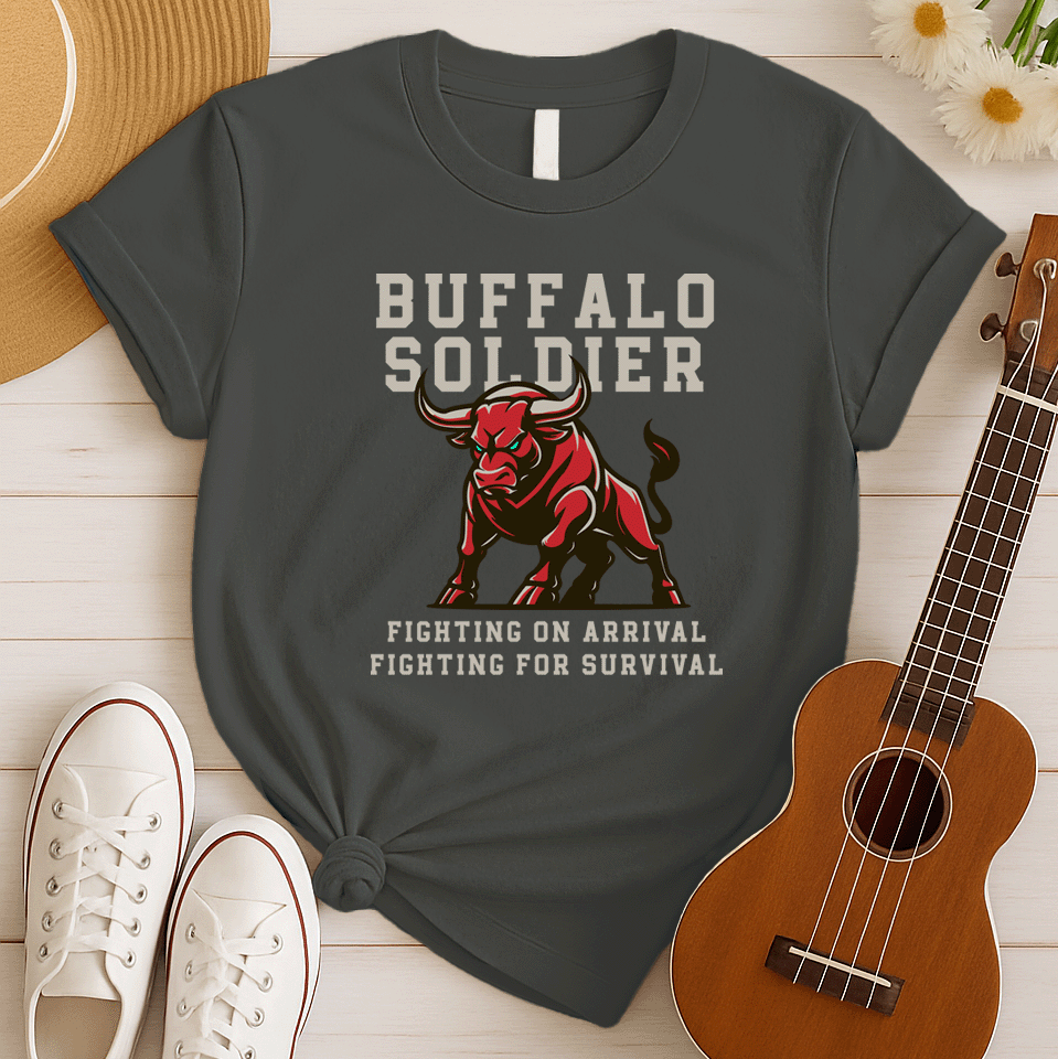 A striking graphic design features a powerfully built red bull with menacing green eyes and prominent horns, depicted in a charging or aggressive stance. The bull's body is outlined in a lighter shade of red, giving it depth. Above the bull, the words "BUFFALO SOLDIER" are written in bold, athletic-style block letters, with "BUFFALO" in white and "SOLDIER" in light grey. Below the bull, two lines of text read "FIGHTING ON ARRIVAL" and "FIGHTING FOR SURVIVAL," both in white, bold, block letters.