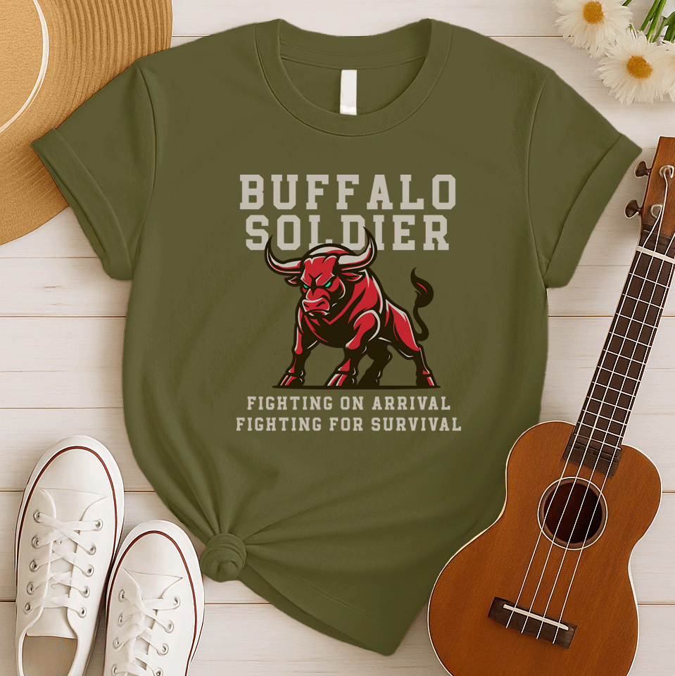 A striking graphic design features a powerfully built red bull with menacing green eyes and prominent horns, depicted in a charging or aggressive stance. The bull's body is outlined in a lighter shade of red, giving it depth. Above the bull, the words "BUFFALO SOLDIER" are written in bold, athletic-style block letters, with "BUFFALO" in white and "SOLDIER" in light grey. Below the bull, two lines of text read "FIGHTING ON ARRIVAL" and "FIGHTING FOR SURVIVAL," both in white, bold, block letters.