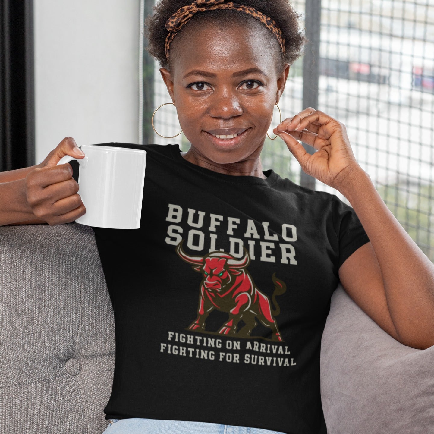 A striking graphic design features a powerfully built red bull with menacing green eyes and prominent horns, depicted in a charging or aggressive stance. The bull's body is outlined in a lighter shade of red, giving it depth. Above the bull, the words "BUFFALO SOLDIER" are written in bold, athletic-style block letters, with "BUFFALO" in white and "SOLDIER" in light grey. Below the bull, two lines of text read "FIGHTING ON ARRIVAL" and "FIGHTING FOR SURVIVAL," both in white, bold, block letters.