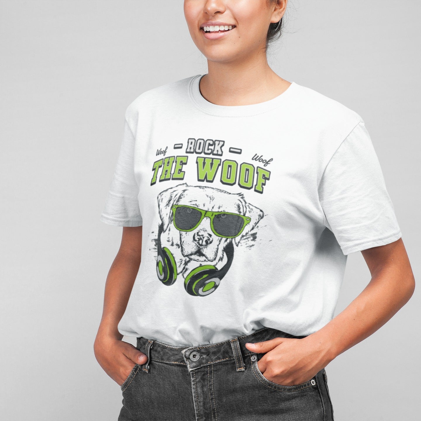 Graphic of a black dog's head wearing bright green-rimmed sunglasses and large headphones with green accents. White distressed text above reads "ROCK" and below the dog's head, large green text with a black outline reads "THE WOOF". Smaller "Woof" texts are on either side of "ROCK". The design suggests rock music, dog lovers, and a cool animal DJ aesthetic. Ideal for pet owners and music enthusiasts.