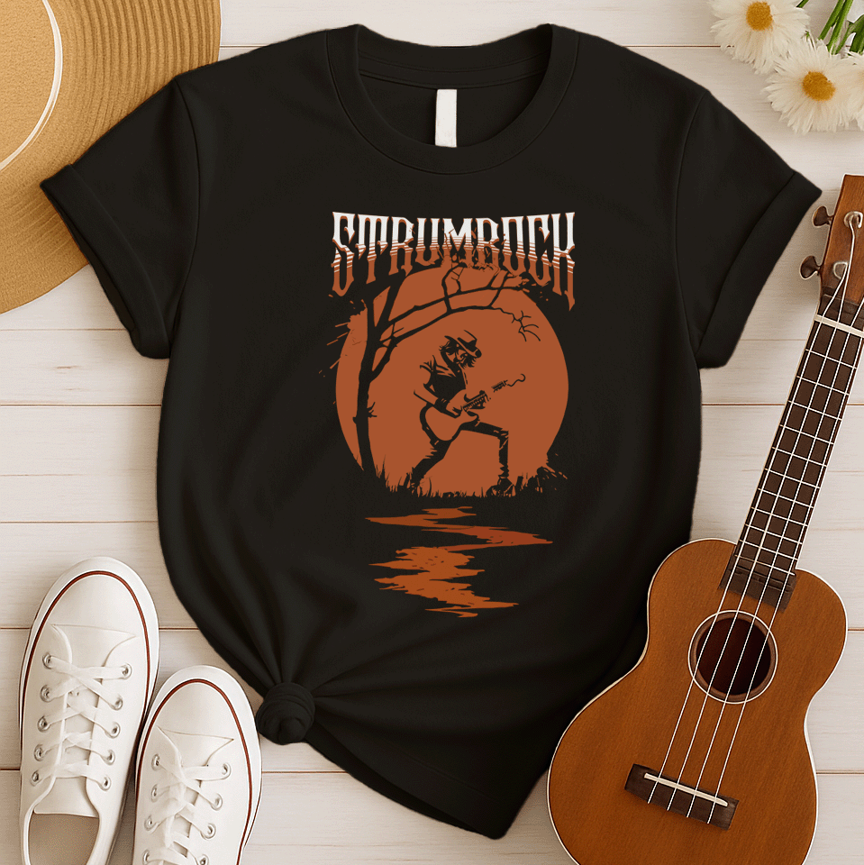 Stylized graphic of a silhouetted guitarist in a hat and jacket, passionately playing an acoustic or electric guitar against a large, glowing orange full moon. A bare tree branch extends over them. Orange text above reads "STRUMROCK". The scene evokes a rock concert or solo performance under the night sky, ideal for guitar players, rock music fans, and musicians.