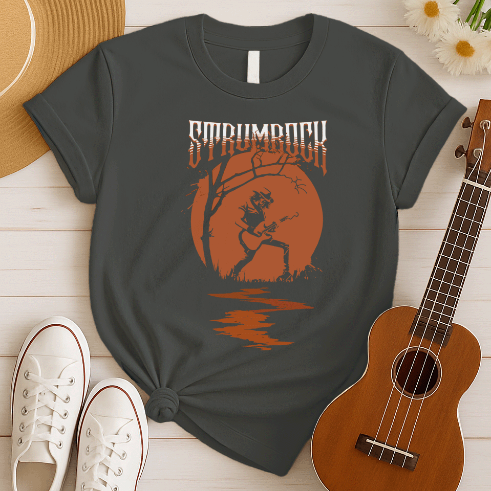 Stylized graphic of a silhouetted guitarist in a hat and jacket, passionately playing an acoustic or electric guitar against a large, glowing orange full moon. A bare tree branch extends over them. Orange text above reads "STRUMROCK". The scene evokes a rock concert or solo performance under the night sky, ideal for guitar players, rock music fans, and musicians.
