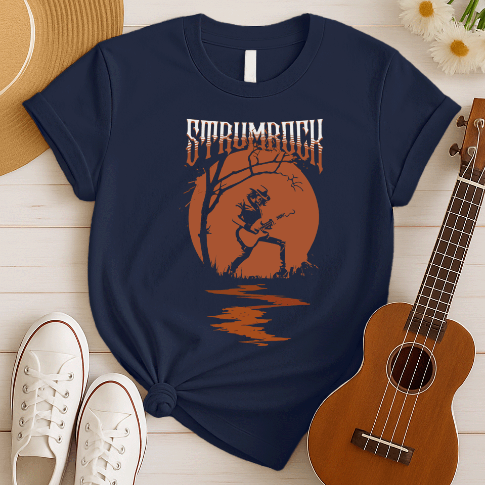 Stylized graphic of a silhouetted guitarist in a hat and jacket, passionately playing an acoustic or electric guitar against a large, glowing orange full moon. A bare tree branch extends over them. Orange text above reads "STRUMROCK". The scene evokes a rock concert or solo performance under the night sky, ideal for guitar players, rock music fans, and musicians.