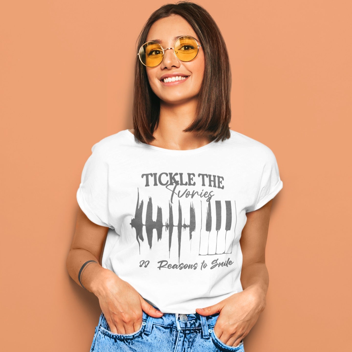 A light background features a graphic with a jagged sound wave transitioning into a set of classic piano keys in dark grey. Below the graphic, dark grey text reads "88 Reasons to Smile". The design prominently features text at the top, "TICKLE THE Ivories". This image symbolizes the joy of music, piano playing, and musical happiness, ideal for pianists and music enthusiasts.