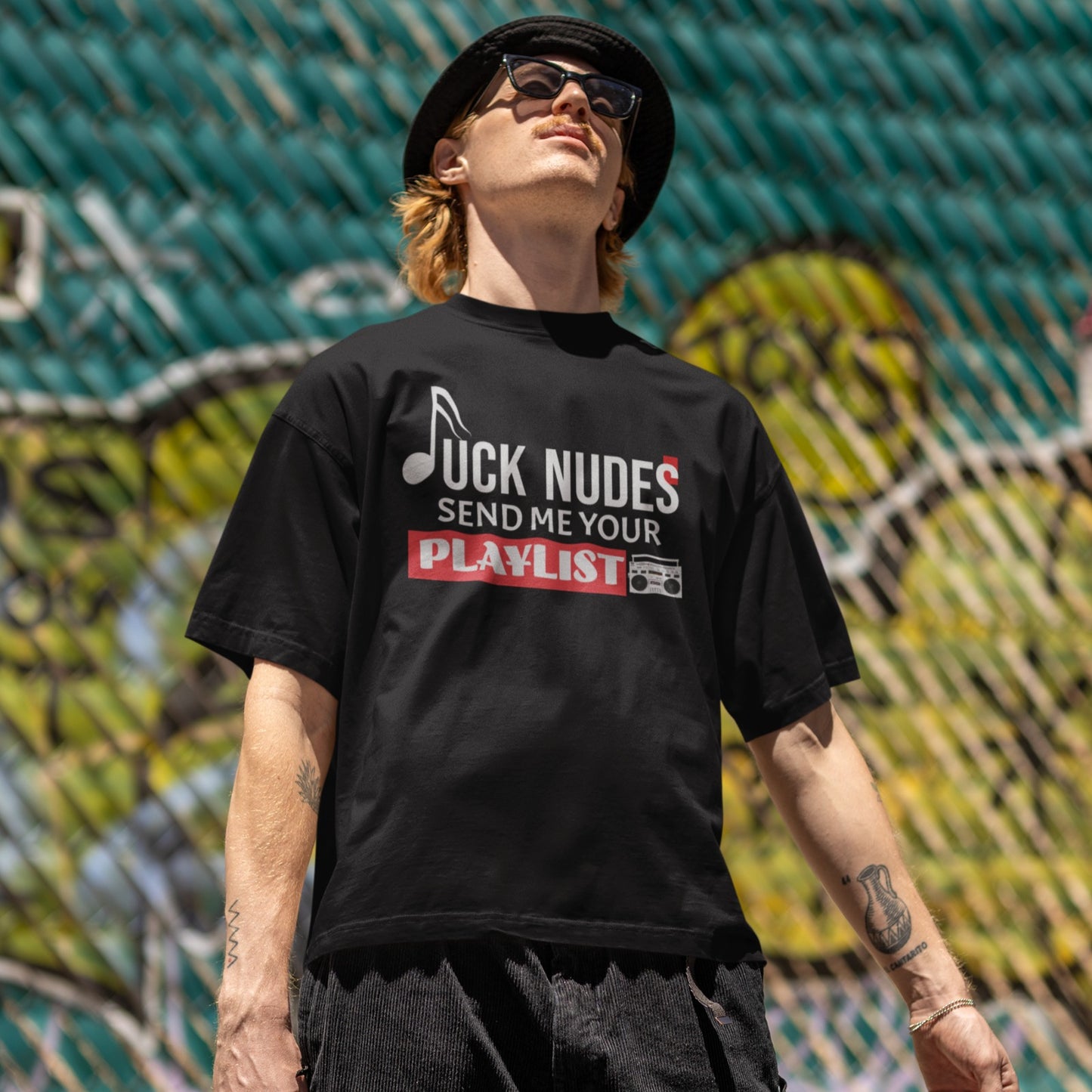 A dark black background features white text that reads "JUCK NUDES" with the "J" stylized as a musical note, implying "F**K NUDES". Below this, more white text says "SEND ME YOUR". A large red rectangular block below that contains the white text "PLAYLIST". In the bottom right corner, a detailed grey and black retro boombox (radio cassette player) is visible. The design is humorous and expresses a strong passion for music and playlists, ideal for music lovers and DJ fans.