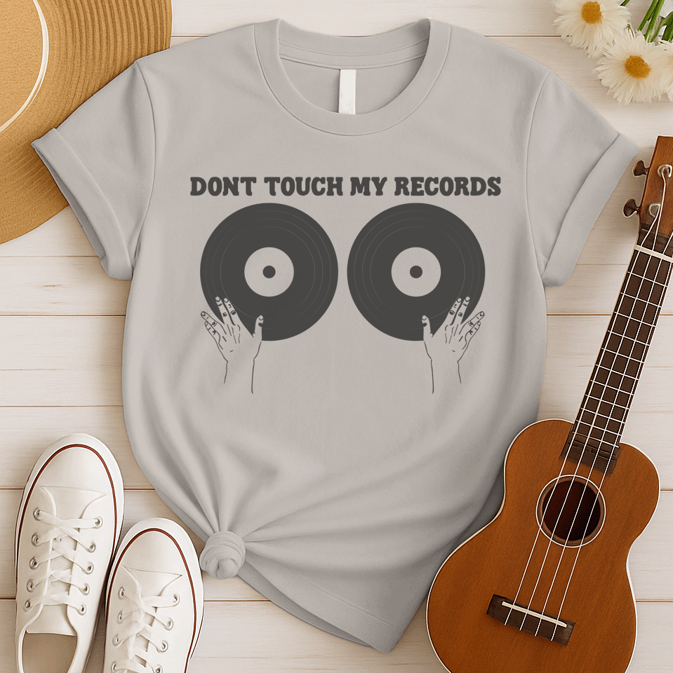 A black background features the bold, capitalized text "DONT TOUCH MY RECORDS" at the top. Below, two large, dark grey vinyl records are depicted side-by-side, with two outlined hands reaching up from the bottom, appearing to cup or touch the records. The design is humorous, symbolizing a possessive love for music, vinyl records, and record collecting, ideal for audiophiles and music fans.