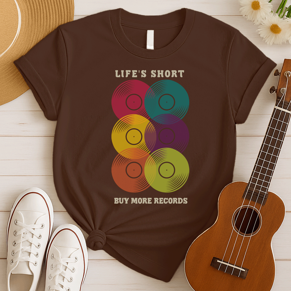 A black background features six vertically stacked, colorful vinyl records (LP records) with visible grooves and black center labels. The record colors include red, teal, yellow, purple, orange, and green. At the top, the distressed text "LIFE'S SHORT" is present, and at the bottom, the distressed text "BUY MORE RECORDS" is visible. The design is a clear celebration of vinyl culture and music collecting.