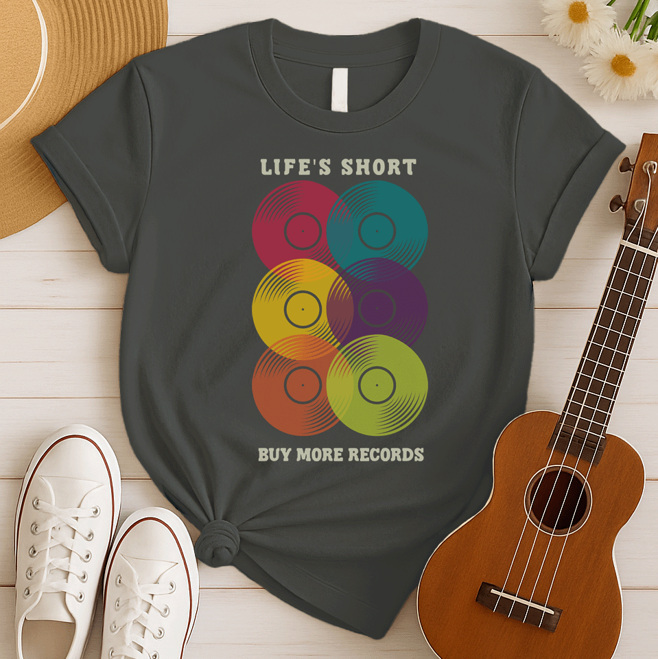 A black background features six vertically stacked, colorful vinyl records (LP records) with visible grooves and black center labels. The record colors include red, teal, yellow, purple, orange, and green. At the top, the distressed text "LIFE'S SHORT" is present, and at the bottom, the distressed text "BUY MORE RECORDS" is visible. The design is a clear celebration of vinyl culture and music collecting.