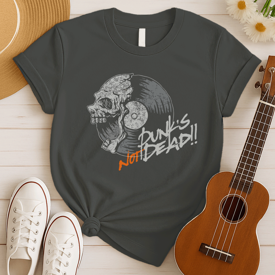 A black background features a stylized illustration of a grey human skull with a crack on its forehead, fused with a vinyl record. The record's grooves and central light grey area are visible. To the right, the distressed grey text reads "Punk's", followed by distressed white text "Not Dead!!". Below this, the orange distressed text "NOT DEAD!!" provides emphasis. The design combines punk music themes with skull imagery and vinyl records.