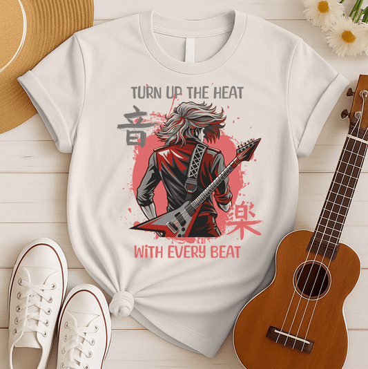 A black background features the distressed grey text "TURN UP THE HEAT" at the top. Below, a stylized illustration of a rock guitarist is seen from behind, with long, flowing grey hair, wearing a black and red leather jacket. The guitarist holds a grey and red angular electric V-shaped guitar. Behind the figure, a distressed red circle contains stylized black Japanese characters. At the bottom, the distressed white text reads "WITH EVERY BEAT". The design portrays an energetic heavy metal or hard rock theme