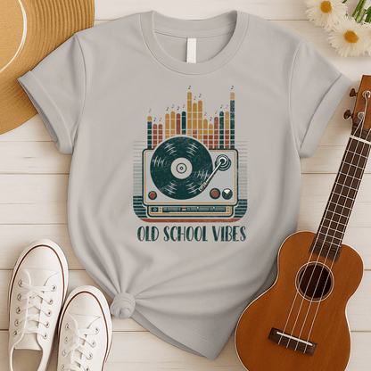 A vibrant, distressed graphic featuring a large turntable with a vinyl record spinning, its tone arm positioned over the record. Behind the turntable, vertical equalizer bars in shades of brown, orange, yellow, and red rise upwards, with small music notes floating above them. Bold, distressed text reads "OLD SCHOOL VIBES". The design evokes retro music and DJ culture.