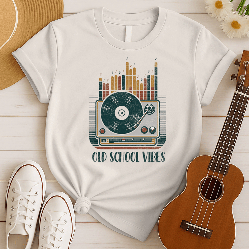 A vibrant, distressed graphic featuring a large turntable with a vinyl record spinning, its tone arm positioned over the record. Behind the turntable, vertical equalizer bars in shades of brown, orange, yellow, and red rise upwards, with small music notes floating above them. Bold, distressed text reads "OLD SCHOOL VIBES". The design evokes retro music and DJ culture.