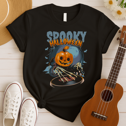 A black background features the distressed light blue text "SPOOKY" and distressed orange text "HALLOWEEN" with a white outline at the top. Below, a large, smiling jack-o'-lantern (pumpkin head) wearing a dark cloak is shown operating a DJ turntable. Skeletal hands with long fingers extend from the cloak over the turntable, manipulating it. In the background, there's a large, pale full moon, silhouetted bats flying, and cloud-like mist. The design represents a Halloween-themed DJ ready for a spooky music pa