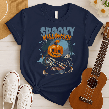A black background features the distressed light blue text "SPOOKY" and distressed orange text "HALLOWEEN" with a white outline at the top. Below, a large, smiling jack-o'-lantern (pumpkin head) wearing a dark cloak is shown operating a DJ turntable. Skeletal hands with long fingers extend from the cloak over the turntable, manipulating it. In the background, there's a large, pale full moon, silhouetted bats flying, and cloud-like mist. The design represents a Halloween-themed DJ ready for a spooky music pa