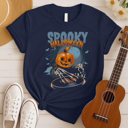 A black background features the distressed light blue text "SPOOKY" and distressed orange text "HALLOWEEN" with a white outline at the top. Below, a large, smiling jack-o'-lantern (pumpkin head) wearing a dark cloak is shown operating a DJ turntable. Skeletal hands with long fingers extend from the cloak over the turntable, manipulating it. In the background, there's a large, pale full moon, silhouetted bats flying, and cloud-like mist. The design represents a Halloween-themed DJ ready for a spooky music pa