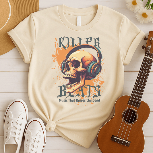 A light grey background with orange paint splatters features a stylized, detailed, orange and yellow human skull wearing large, teal and blue headphones. Distressed grey text above reads "KILLER" and below, "BEATS". Below that, smaller dark grey text says "Music That Raises the Dead". The design is a bold representation of music power and skull art.