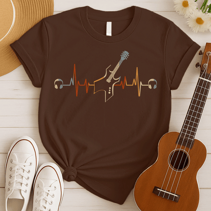 A striking graphic design presents a black electric guitar, notable for its sharp, angular body and a light blue fretboard, positioned centrally within a vibrant, horizontally stretching electrocardiogram (ECG) heartbeat line that shifts from warm reds and oranges to cooler yellows and light blues. A pair of white over-ear headphones are situated at either extremity of the heartbeat line, symbolizing the energetic connection between musical passion and the rhythm of life