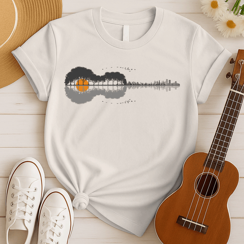 A graphic design features an acoustic guitar silhouette, its body formed by dark gray trees with an orange sun or moon appearing through them. The guitar's neck transitions into a gray sound wave pattern, ending in a minimalist cityscape outline. Flocks of birds fly above and below the design, creating a harmonious blend of nature, music, and urban elements.