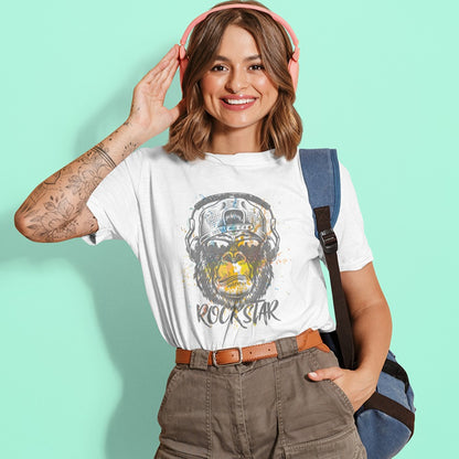A grunge-style graphic features a detailed gorilla head wearing headphones, with the lower half of its face replaced by a textured splash of orange and yellow paint. The gorilla's fur and the headphones are rendered in shades of grey with distressed effects. Below the powerful primate, the word "ROCKSTAR" is emblazoned in a distressed white font with flecks of colorful paint matching the face. This striking design embodies raw power and musical rebellion.