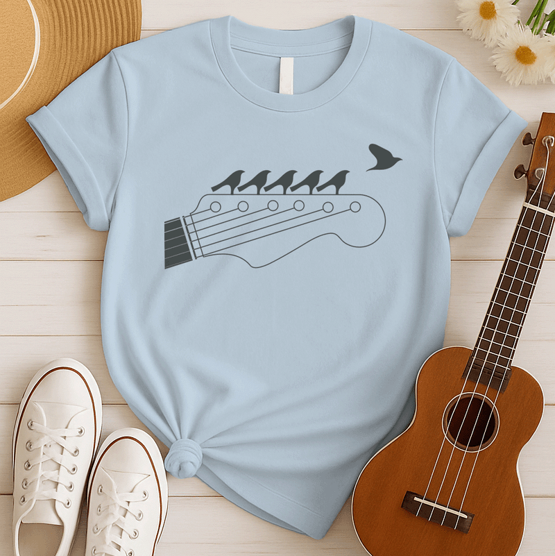 Stylized black graphic of a guitar headstock with tuning pegs and strings. Five small birds are perched in silhouette on the guitar strings, and one bird is depicted flying away in the top right corner. The design suggests musical harmony, freedom, and a connection between nature and guitar music. Ideal for guitar enthusiasts and musicians.