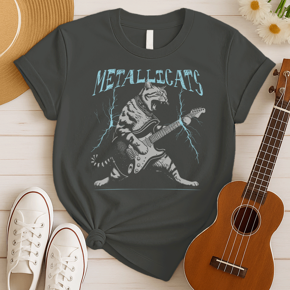 Dynamic graphic of a gray striped tabby cat with its mouth open, appearing to roar, passionately playing a black and white electric guitar. Blue lightning bolts emanate from the guitar. Text above reads "METALLICATS". The cat wears a studded collar. Ideal for heavy metal fans, rock music lovers, guitarists, and cat lovers.