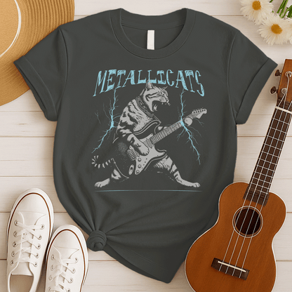 Dynamic graphic of a gray striped tabby cat with its mouth open, appearing to roar, passionately playing a black and white electric guitar. Blue lightning bolts emanate from the guitar. Text above reads "METALLICATS". The cat wears a studded collar. Ideal for heavy metal fans, rock music lovers, guitarists, and cat lovers.