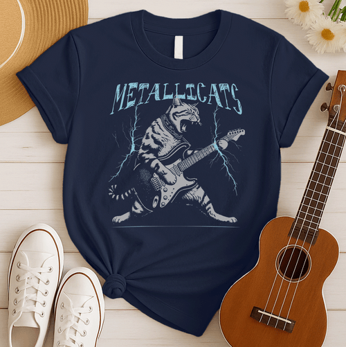Dynamic graphic of a gray striped tabby cat with its mouth open, appearing to roar, passionately playing a black and white electric guitar. Blue lightning bolts emanate from the guitar. Text above reads "METALLICATS". The cat wears a studded collar. Ideal for heavy metal fans, rock music lovers, guitarists, and cat lovers.