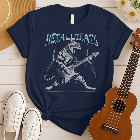 Dynamic graphic of a gray striped tabby cat with its mouth open, appearing to roar, passionately playing a black and white electric guitar. Blue lightning bolts emanate from the guitar. Text above reads "METALLICATS". The cat wears a studded collar. Ideal for heavy metal fans, rock music lovers, guitarists, and cat lovers.