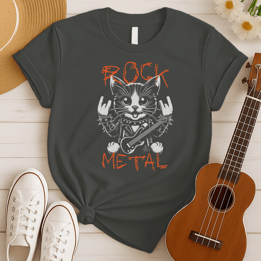 Close-up graphic of a cute black and white cat wearing a studded leather jacket and wristbands, holding a mini electric guitar, and making rock and roll hand gestures ("metal horns") with both paws. Orange distressed text above reads "ROCK" and below reads "METAL". The design has a gritty, punk rock aesthetic, ideal for rock music fans, metalheads, and cat lovers.